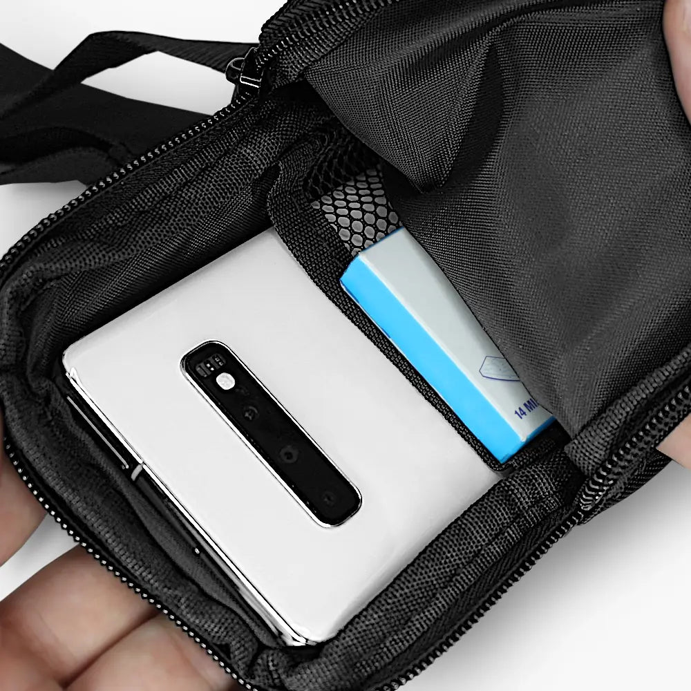 Innenansicht einer schwarzen mini Chest Bag mit einem Smartphone und einer blauen Verpackung in den Fächern